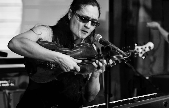 female musician playing violin on stage with microphone black and white music performance artistry