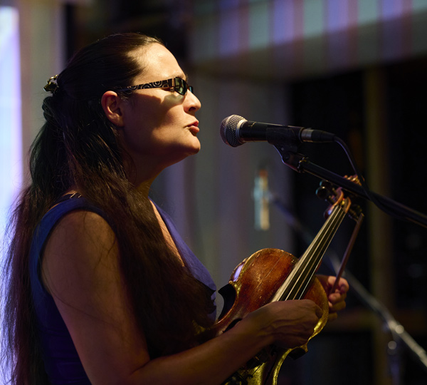 female musician singing with violin on stage during performance